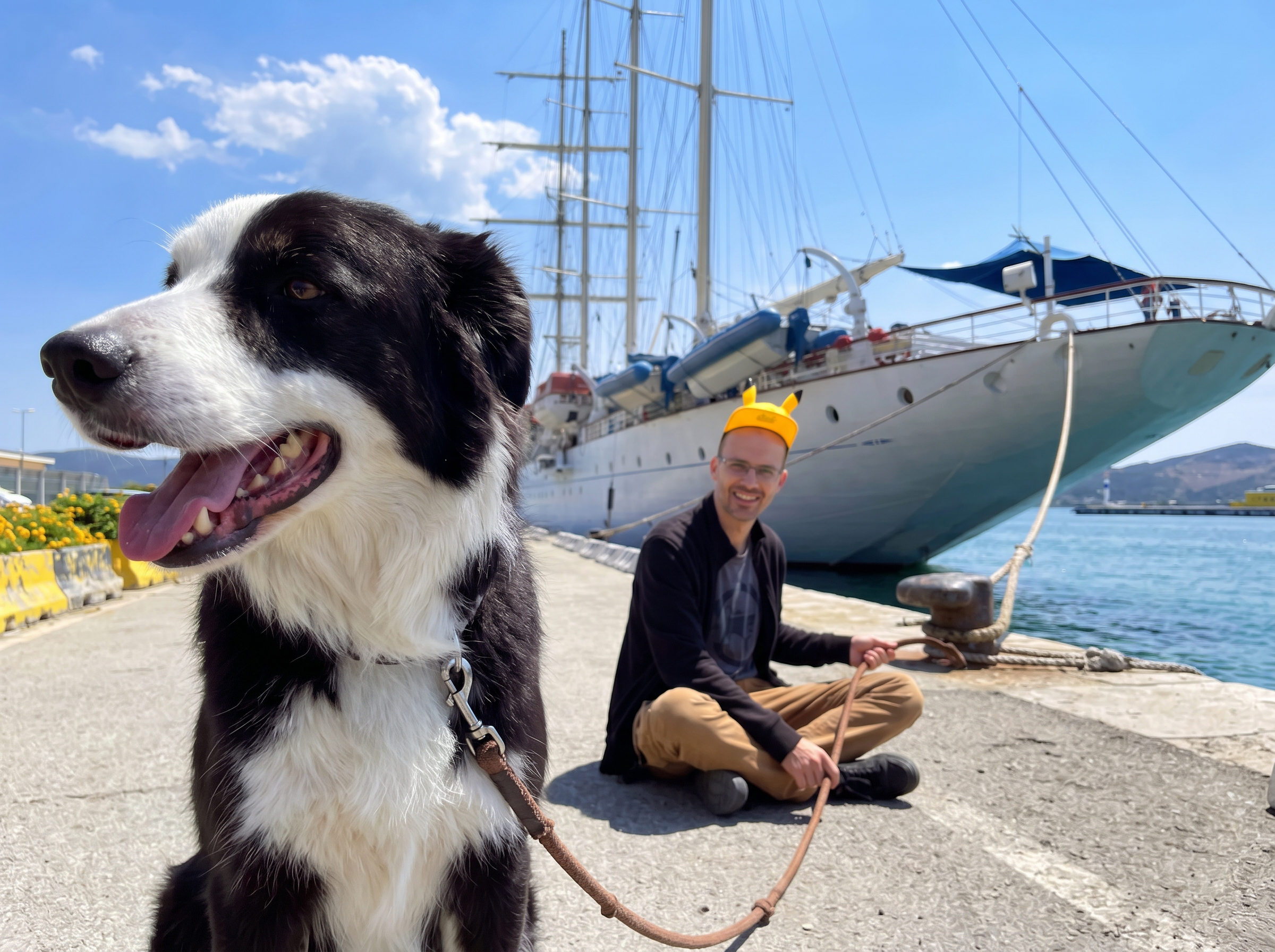 Hund mit Halter vor einem Segelschiff im Hafen
