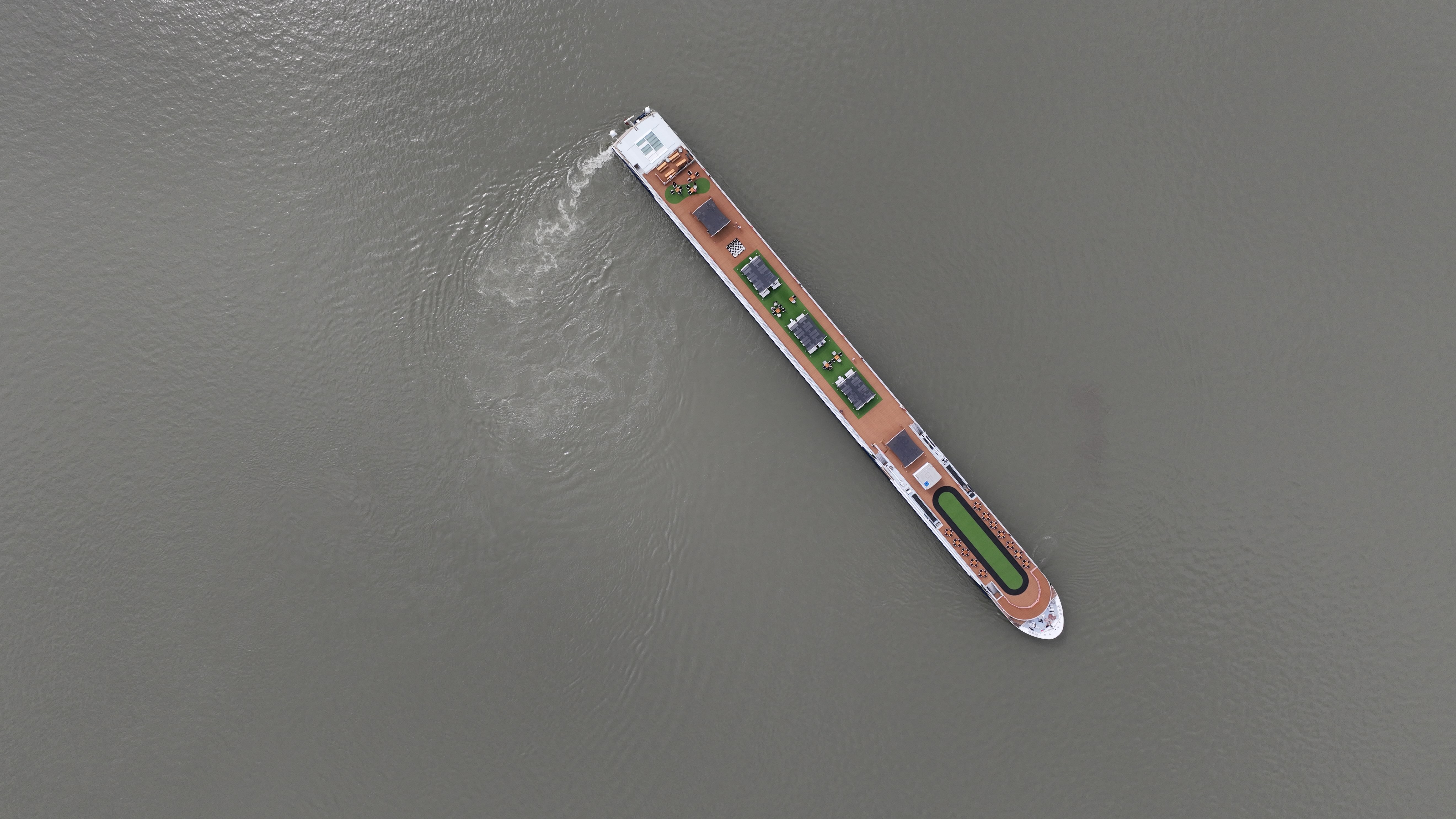 Luftaufnahme eines fahrenden Flusskreuzfahrtschiffs auf ruhigem Gewässer während einer hundefreundlichen Reise