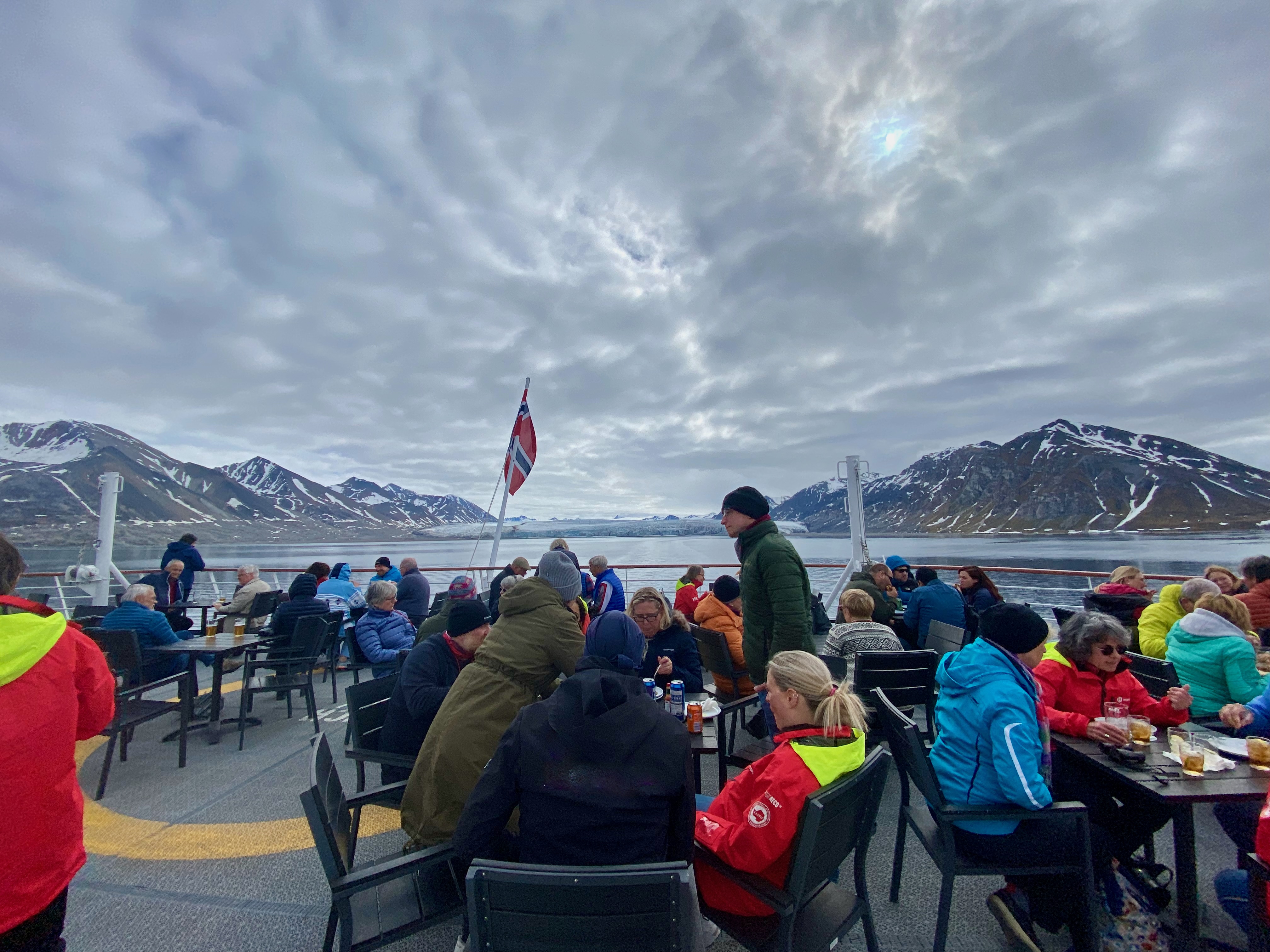 Norwegen Kreuzfahrt mit Hund an Deck mit Gästen vor Fjordlandschaft und Bergen